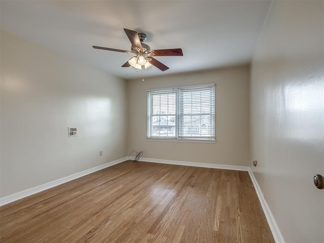 spare room featuring wood finished floors, baseboards, and ceiling fan