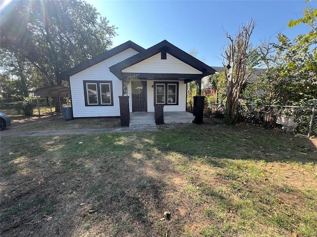 bungalow-style home with covered porch, a carport, and a front lawn