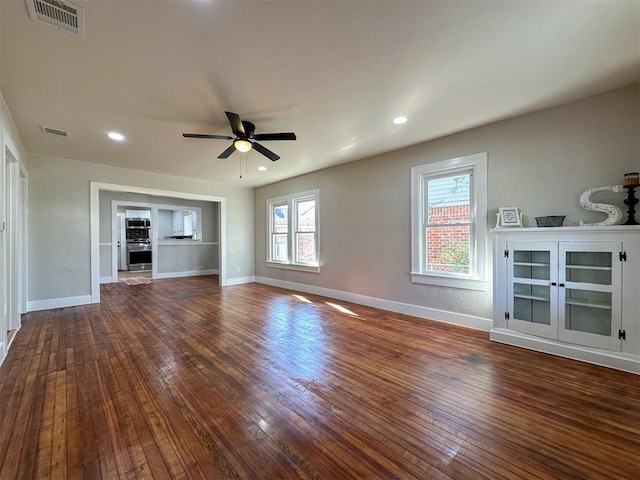 unfurnished living room with visible vents, ceiling fan, baseboards, and hardwood / wood-style flooring