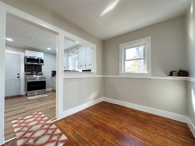 interior space with recessed lighting, light wood-style flooring, appliances with stainless steel finishes, white cabinetry, and baseboards