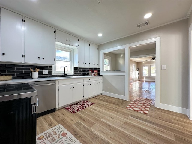 kitchen featuring tasteful backsplash, visible vents, dishwasher, light wood-style flooring, and a sink