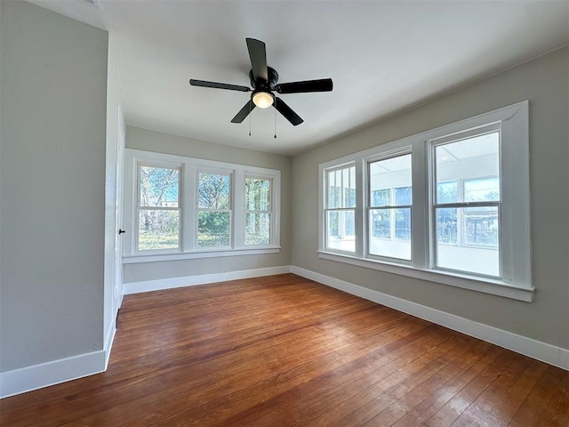 unfurnished room featuring a ceiling fan, dark wood-style flooring, and baseboards