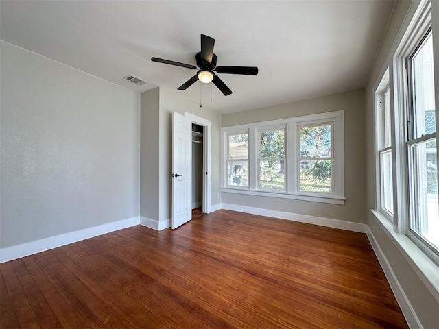 unfurnished bedroom with ceiling fan, dark wood-style flooring, visible vents, baseboards, and a closet