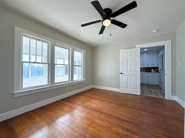 interior space with dark wood-style floors, baseboards, and a ceiling fan