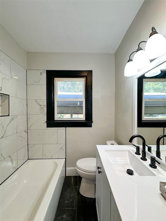 bathroom with baseboards, marble finish floor, toilet, and a healthy amount of sunlight