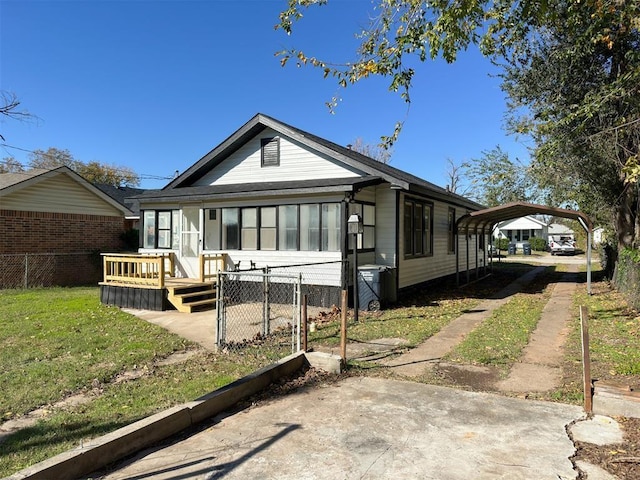 bungalow-style home with a detached carport, a sunroom, fence, and a wooden deck