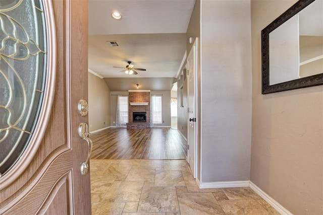 entryway with visible vents, baseboards, ceiling fan, stone finish flooring, and a fireplace