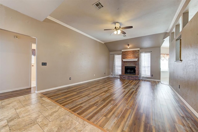 unfurnished living room with lofted ceiling, visible vents, a ceiling fan, a brick fireplace, and wood finished floors