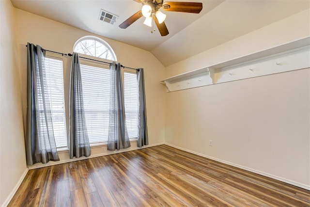 spare room featuring ceiling fan, wood finished floors, visible vents, baseboards, and vaulted ceiling