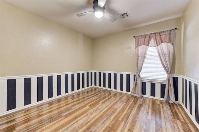 unfurnished room featuring wallpapered walls, ceiling fan, visible vents, and wood finished floors