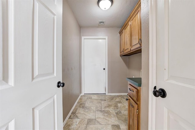 laundry room with stone finish floor, visible vents, and baseboards