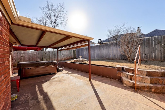 view of patio featuring a carport, a fenced backyard, and a hot tub