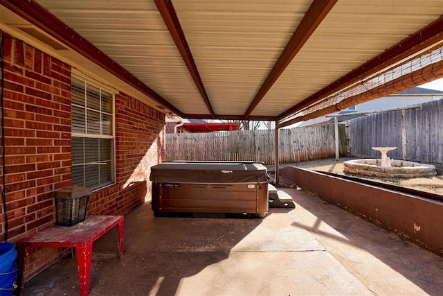 view of patio / terrace with a hot tub and fence