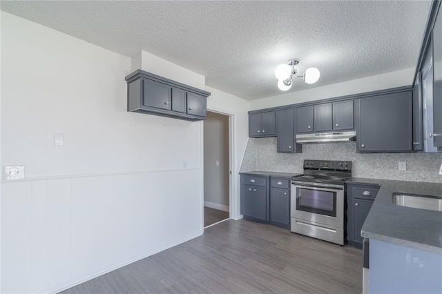 kitchen with dark wood-style flooring, dark countertops, under cabinet range hood, stainless steel electric stove, and a sink