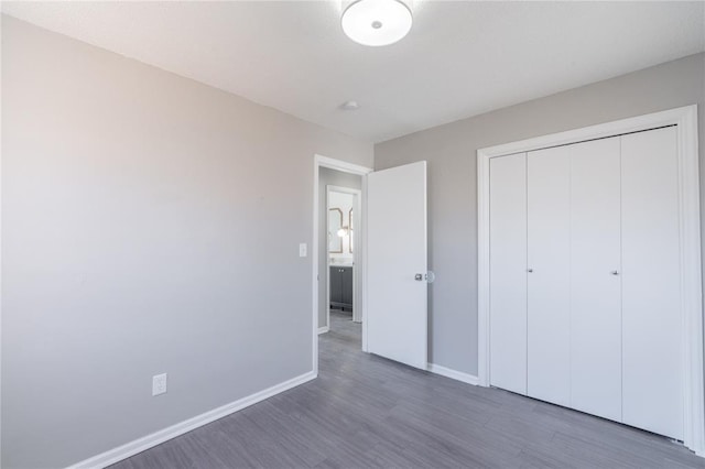unfurnished bedroom with baseboards, wood finished floors, and a closet