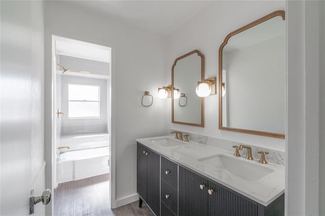 full bathroom with double vanity, a sink, wood finished floors, and a tub to relax in
