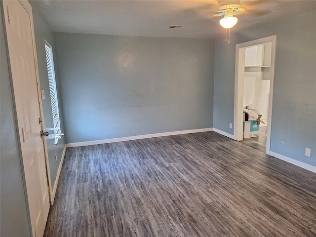 unfurnished room with visible vents, baseboards, ceiling fan, and dark wood-style flooring