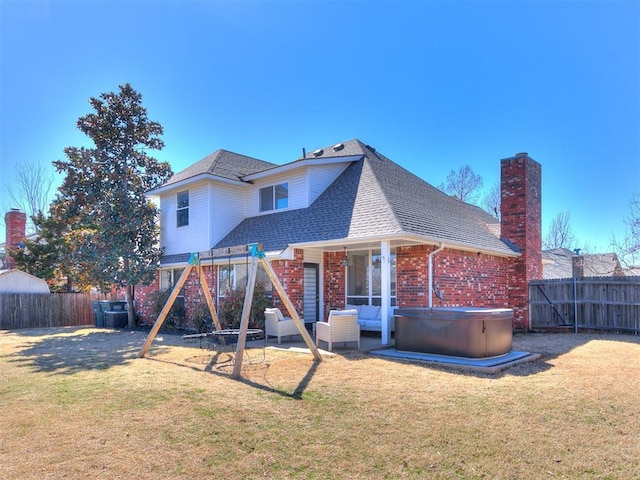 back of property with a yard, a hot tub, a fenced backyard, and a patio