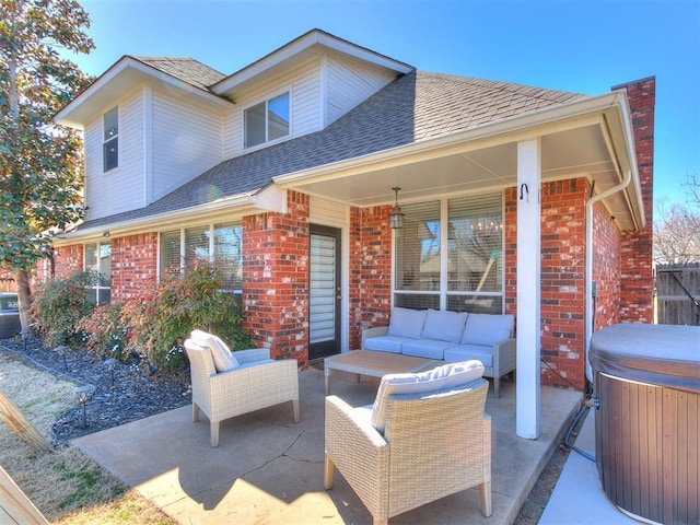 exterior space featuring an outdoor hangout area, a patio, brick siding, and a hot tub