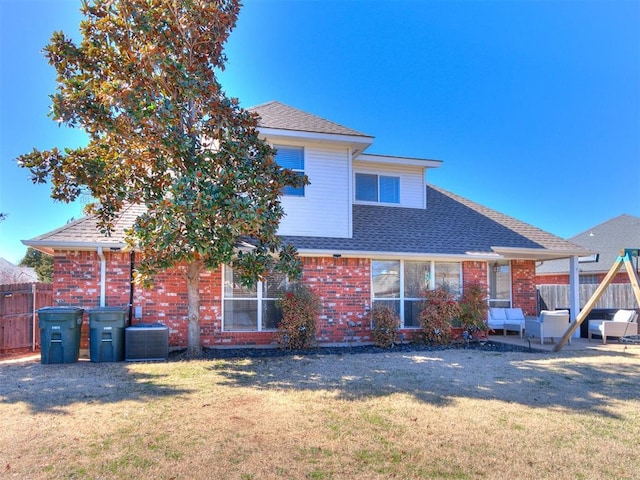 back of house with a yard, brick siding, central AC unit, and fence