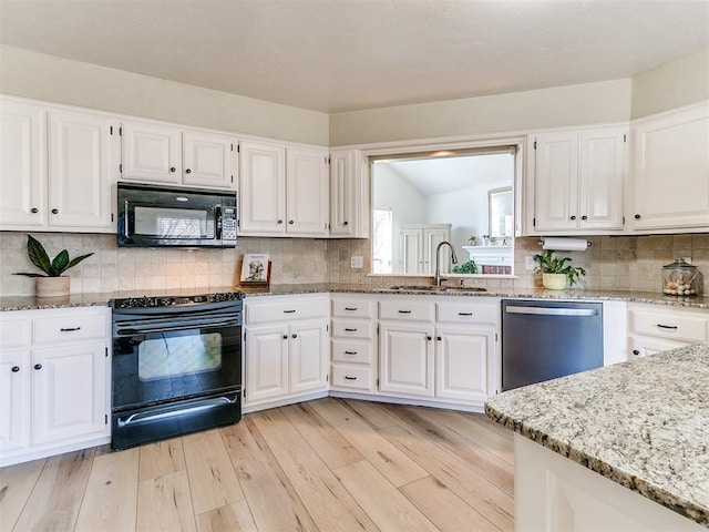 kitchen featuring white cabinets, black appliances, light wood-style floors, and a sink