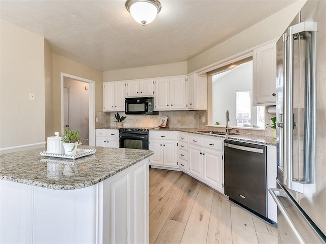 kitchen with black appliances, light wood-style flooring, a sink, and white cabinetry