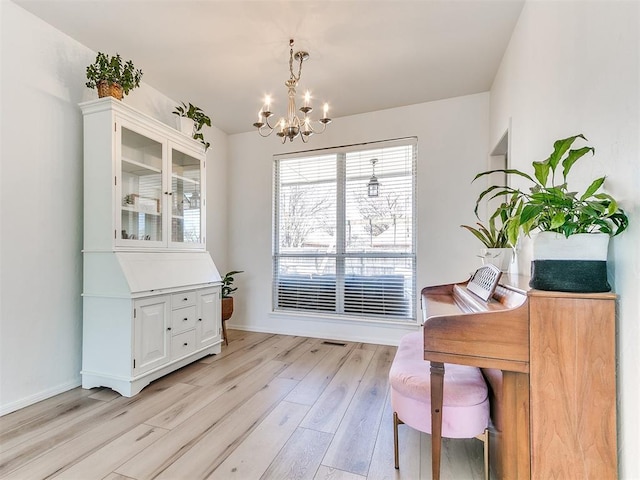 interior space featuring baseboards, light wood-style flooring, and an inviting chandelier