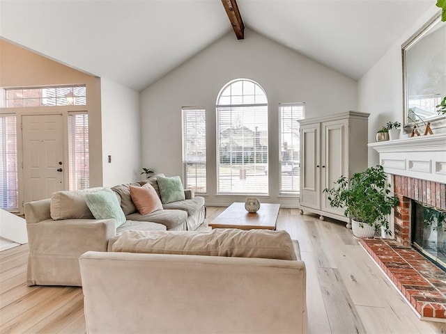 living area featuring light wood-style floors, beam ceiling, a fireplace, and high vaulted ceiling