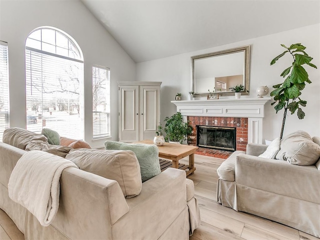 living room with light wood-style floors, vaulted ceiling, and a fireplace