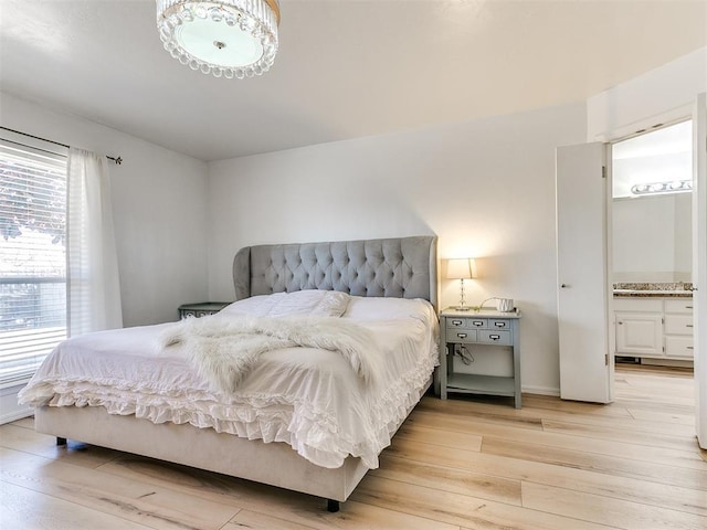 bedroom featuring ensuite bathroom and light wood-style floors