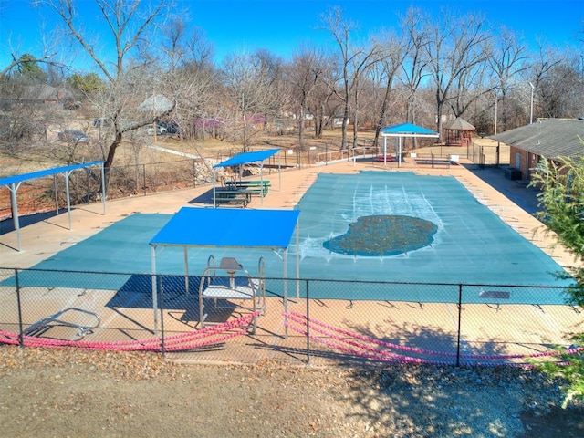 view of swimming pool featuring community basketball court and fence