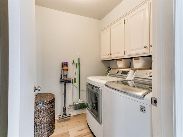 washroom with washer and clothes dryer, light wood-type flooring, and cabinet space