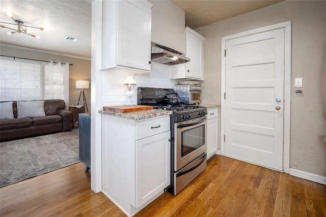 kitchen featuring stainless steel gas range, under cabinet range hood, visible vents, and light wood-style floors