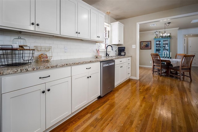 kitchen with white cabinets, backsplash, wood finished floors, stainless steel dishwasher, and a sink