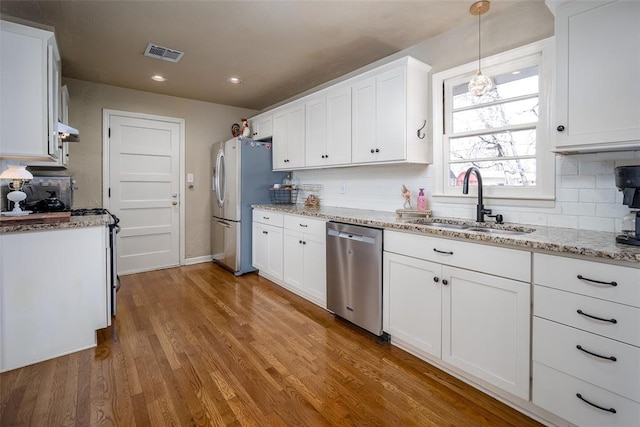 kitchen featuring stainless steel appliances, visible vents, white cabinets, a sink, and wood finished floors