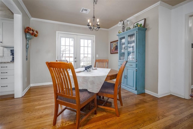 dining space with french doors, visible vents, light wood-style flooring, ornamental molding, and baseboards