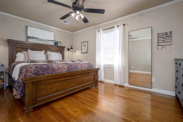 bedroom featuring visible vents, crown molding, and wood finished floors