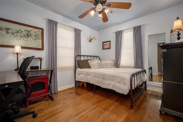 bedroom featuring multiple windows, baseboards, and wood finished floors