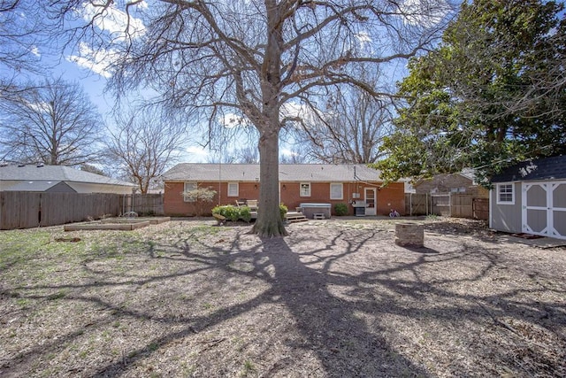 back of property with an outbuilding, a storage unit, a fenced backyard, and brick siding