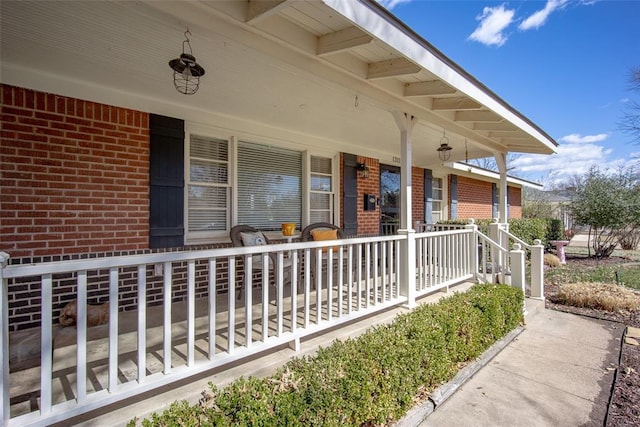 doorway to property featuring covered porch and brick siding