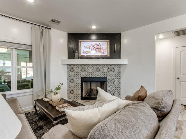 living room with a fireplace, wood finished floors, visible vents, and recessed lighting