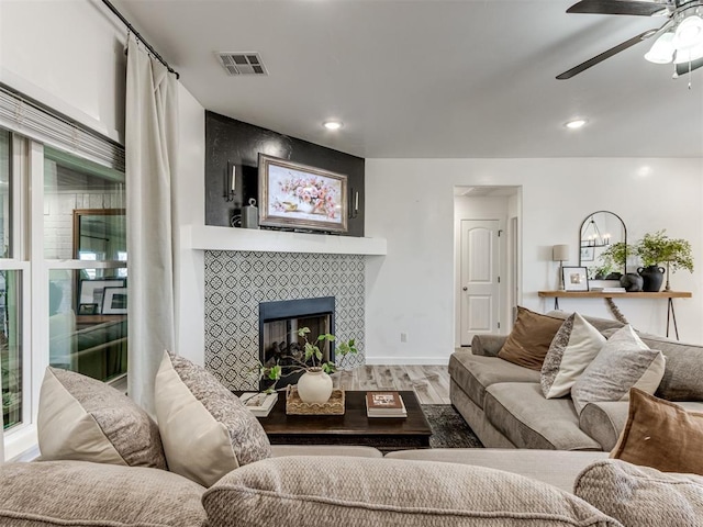 living area featuring visible vents, wood finished floors, ceiling fan with notable chandelier, a fireplace, and recessed lighting