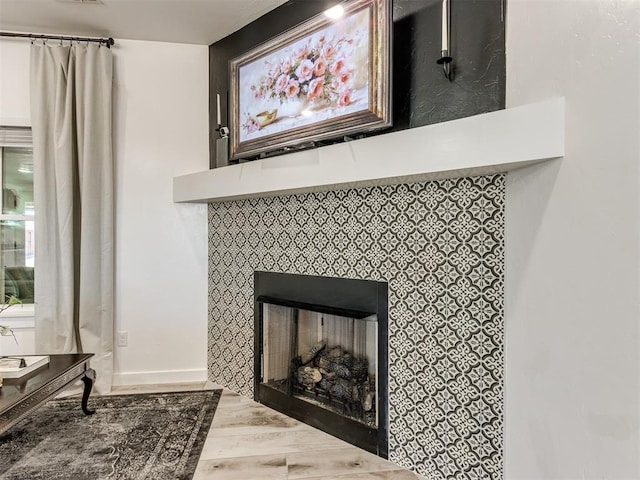 room details featuring a fireplace, wood finished floors, visible vents, and baseboards