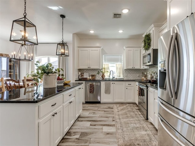 kitchen with visible vents, appliances with stainless steel finishes, white cabinets, and backsplash