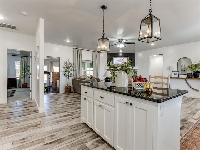 kitchen featuring visible vents, open floor plan, light wood-type flooring, white cabinetry, and pendant lighting