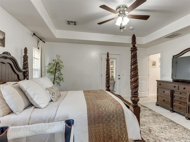 bedroom featuring light carpet, ceiling fan, visible vents, and a tray ceiling