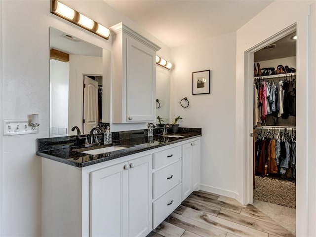 full bathroom featuring double vanity, a sink, a spacious closet, and wood finished floors