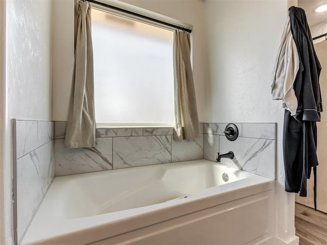 full bathroom featuring a garden tub, a wealth of natural light, and wood finished floors