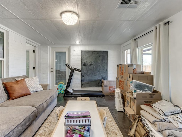 living area with visible vents and brick wall