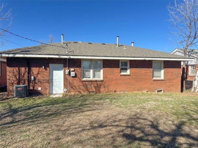 rear view of property featuring a yard, brick siding, a shingled roof, and cooling unit